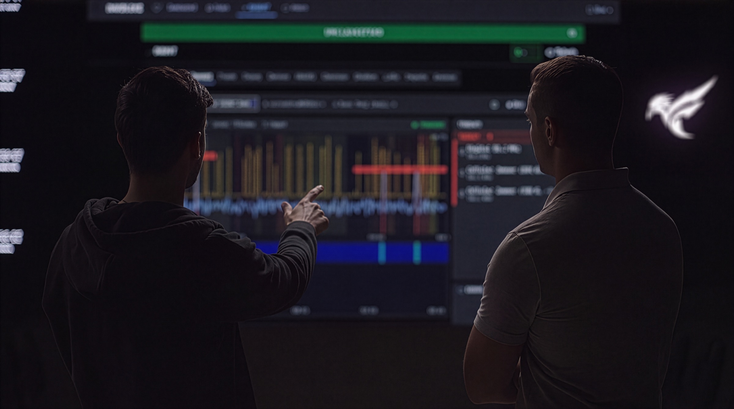 Two operators reading a live spectrum display in a darkened operations room